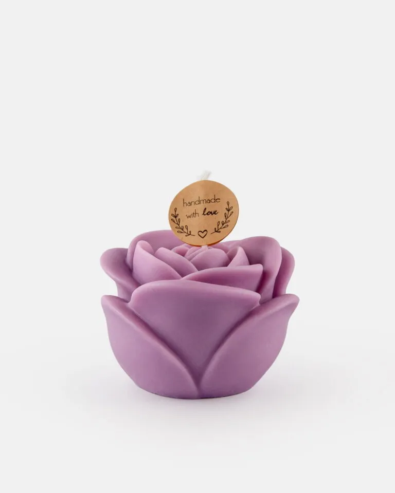 Ręcznie wykonana świeczka w kształcie różowego kwiatu z fioletowym odcieniem, ozdobiona okrągłą zawieszką z napisem „handmade with love” i małym serduszkiem na białym tle.