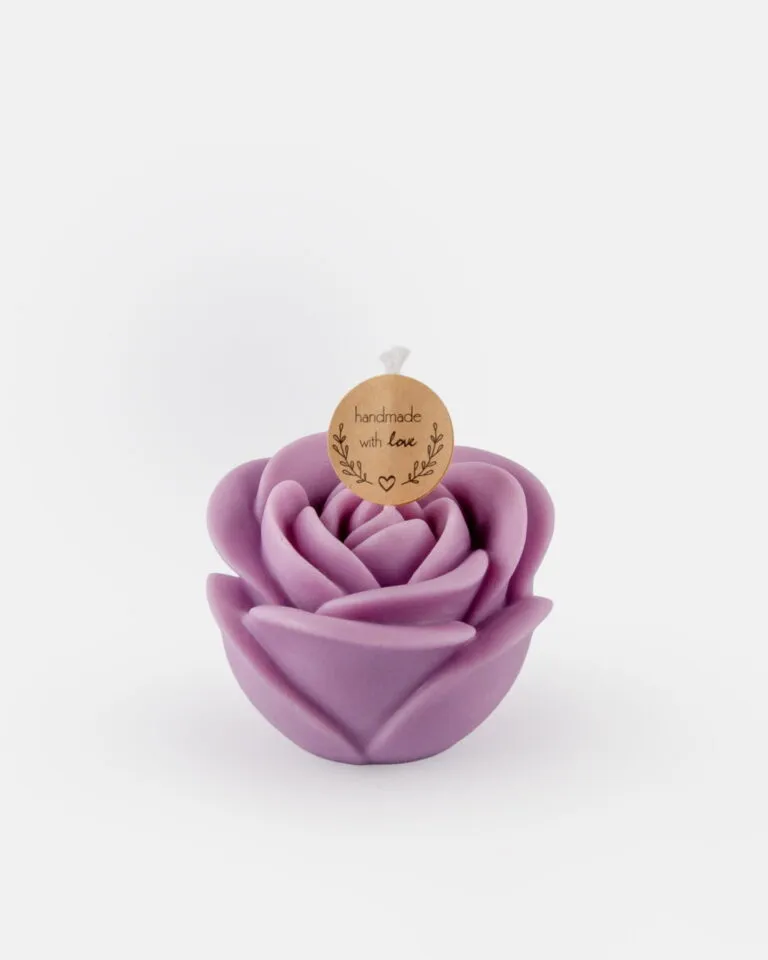 Świeczka sojowa w kształcie róży, w kolorze lawendowym, z okrągłą zawieszką z napisem „handmade with love” przymocowaną do knota, umieszczona na białym tle.
